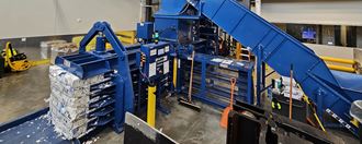 A large blue industrial baler in a warehouse