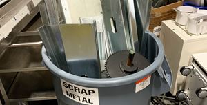 A gray bin filled with scrap metal pieces