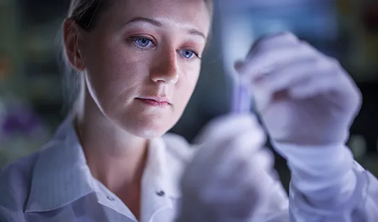 Close-up of a lab worker examining a sample in a lab.
