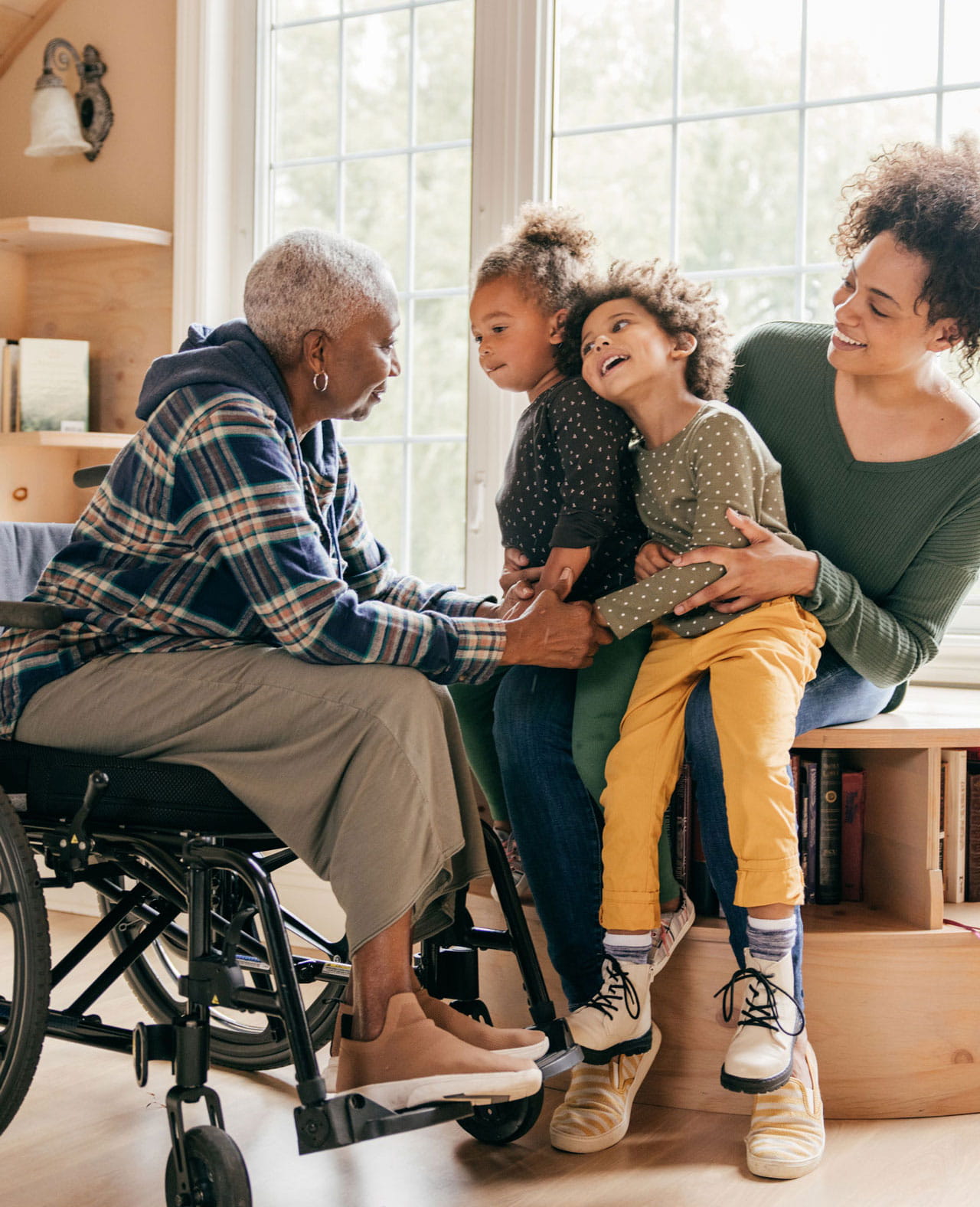 A mother and her two children laughing with their grandmother, who is in a wheelchair.
