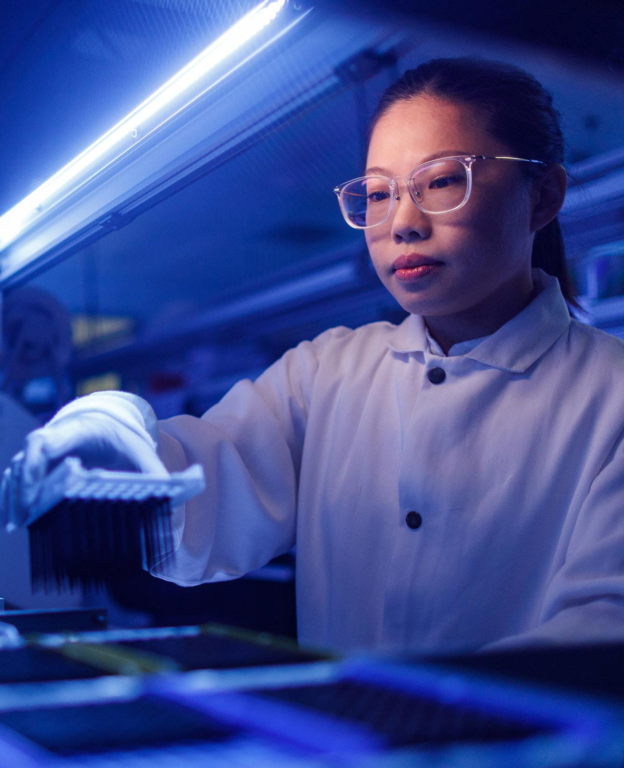 A lab technician placing samples into lab equipment for analysis.