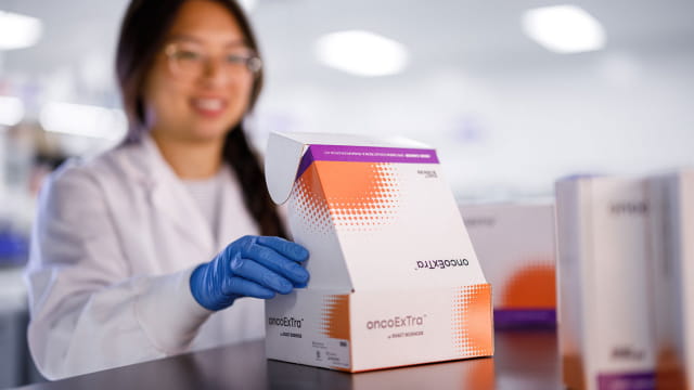An Exact Sciences lab technician opening an OncoExTra test kit box.