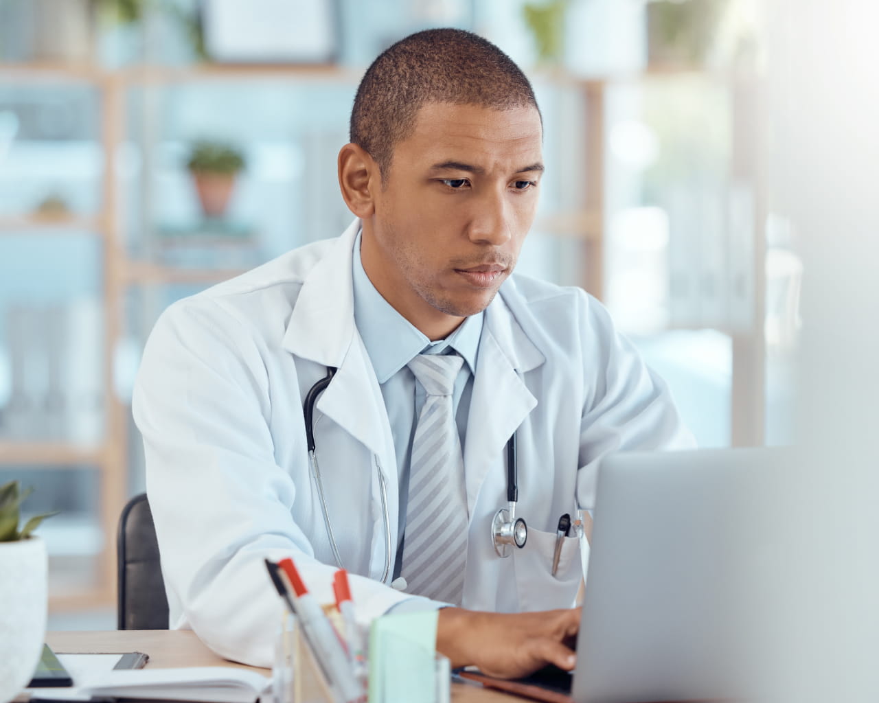 Seated healthcare provider reviewing information on a laptop.