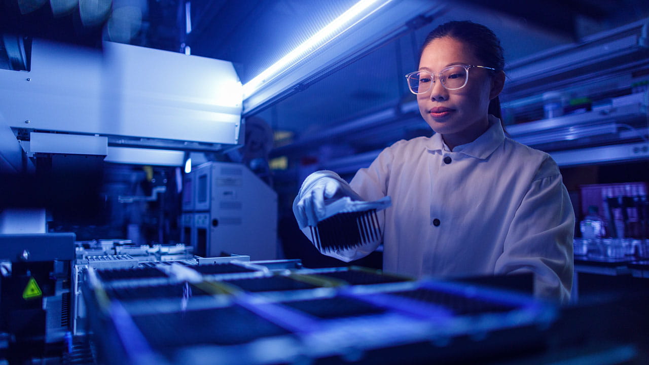 A lab technician placing samples into lab equipment for analysis.