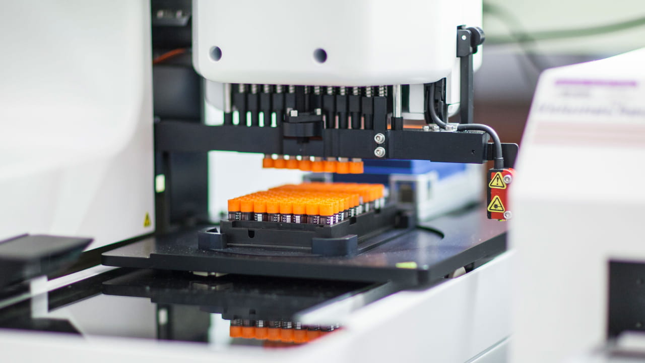 Laboratory machine processing orange test tubes.