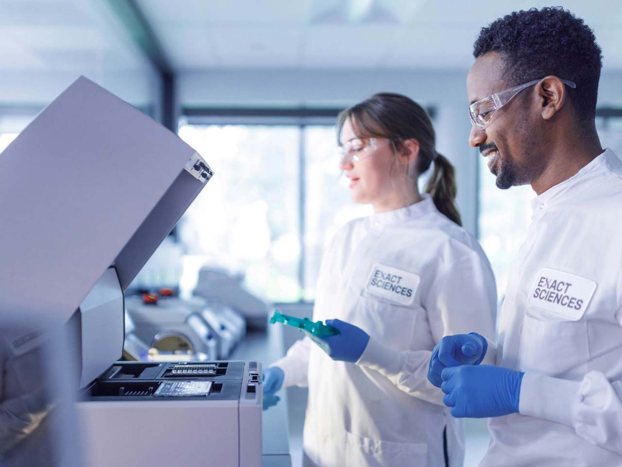 Two Exact Sciences technicians working with lab equipment.