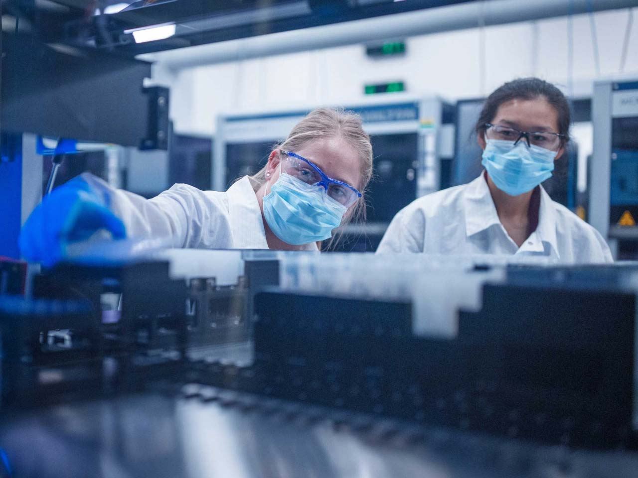 Two lab technicians putting samples into a piece of equipment.