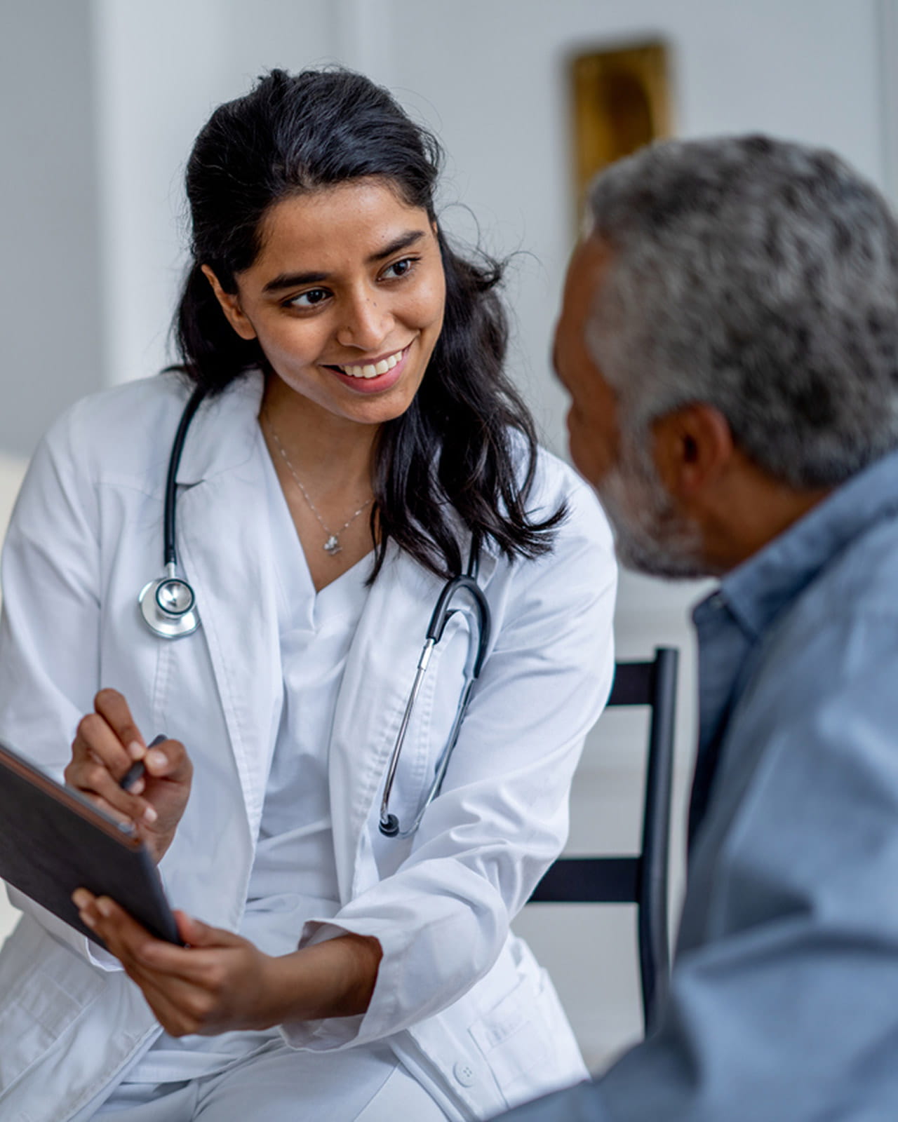 A doctor smiling while talking with a patient.