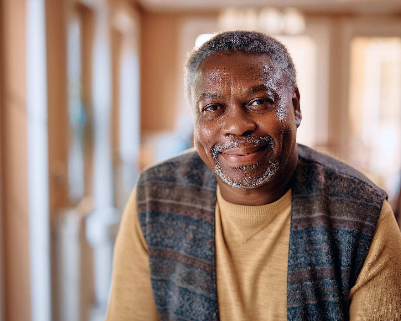 Male patient in a sweater vest smiling.