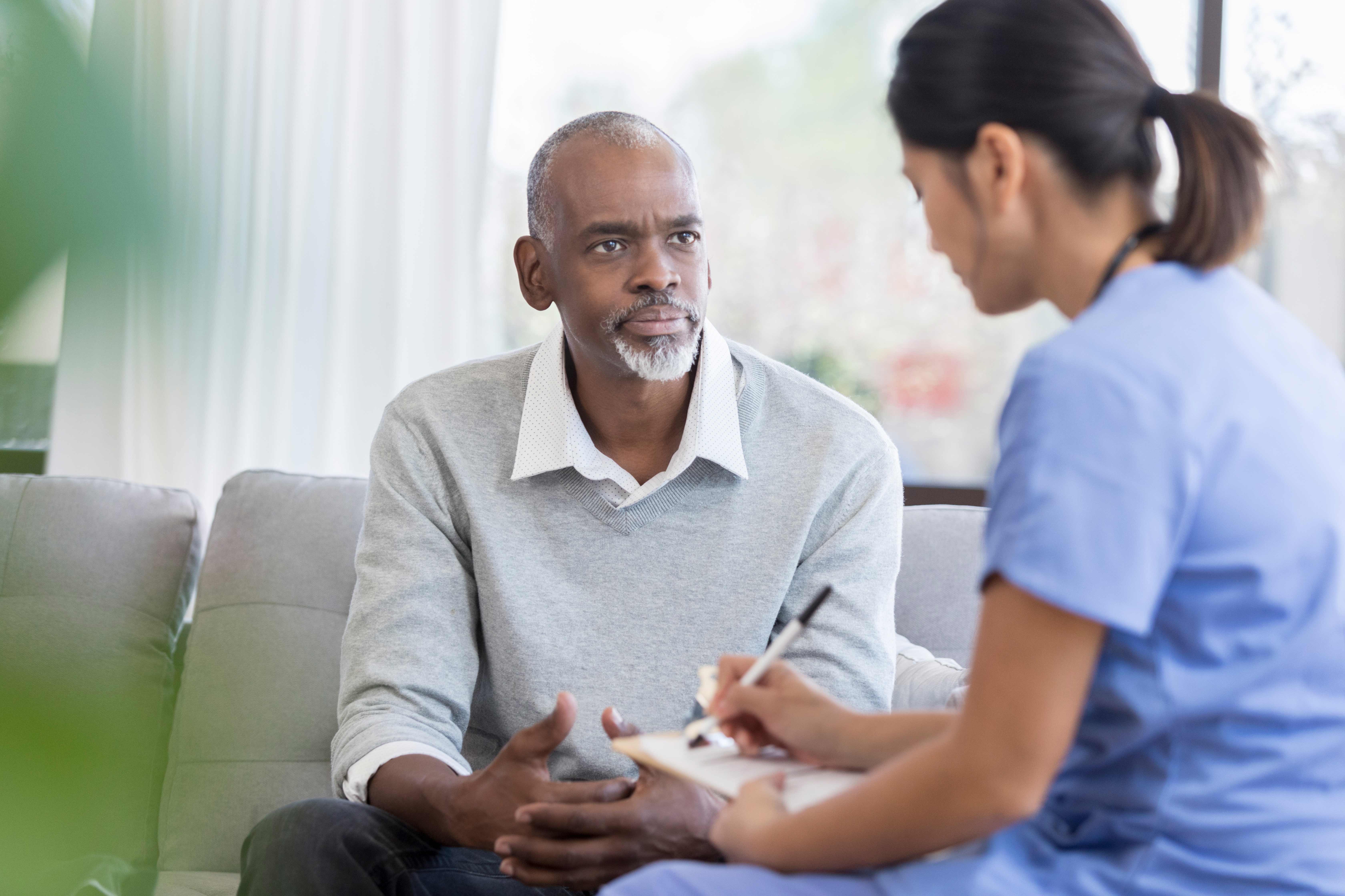 A man sitting down speaking with a nurse.