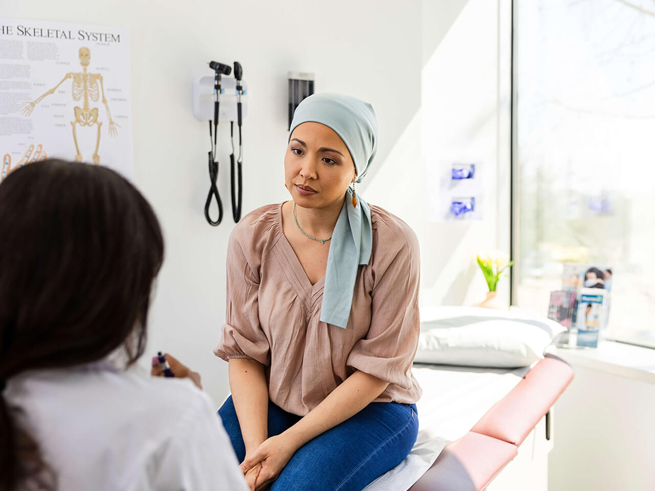 A patient sitting on an exam table talking to her doctor.