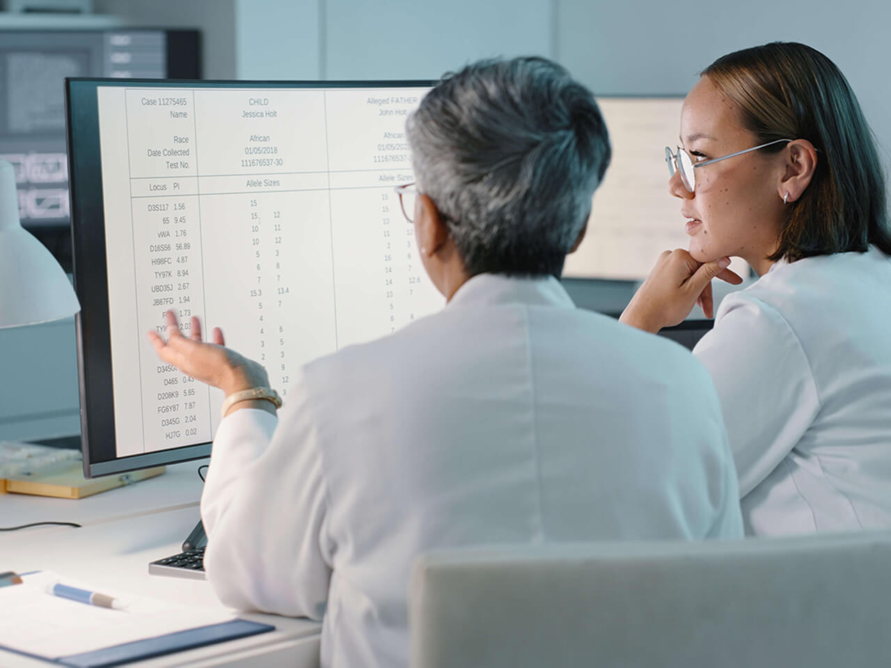 A doctor and nurse talking in front of a computer monitor.