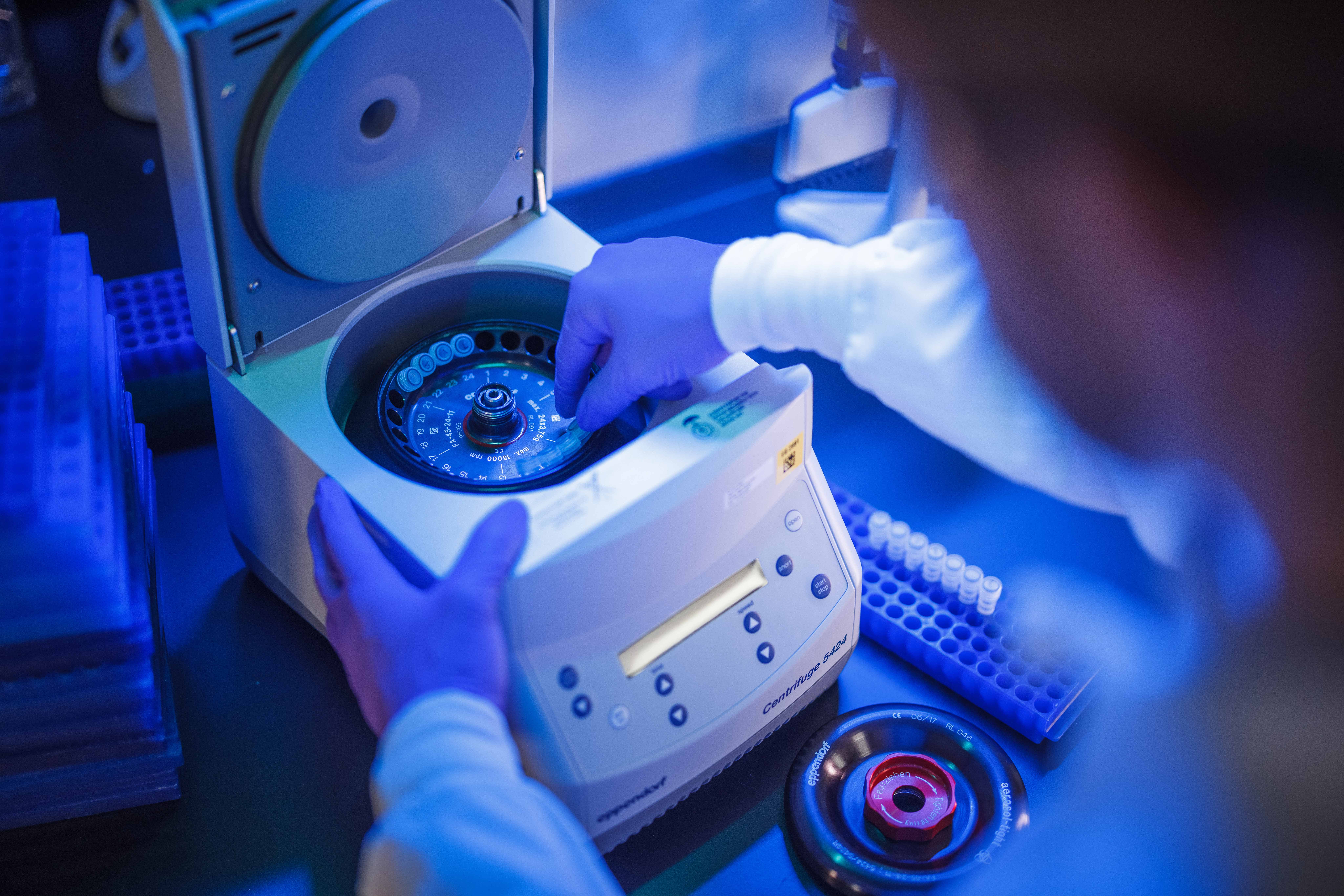 A lab technician loading a centrifuge machine.