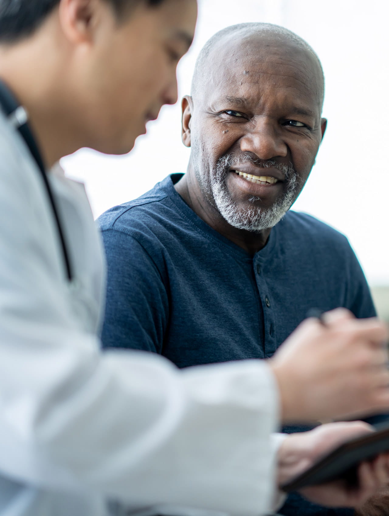 A doctor reviewing test results on an tablet with a patient.