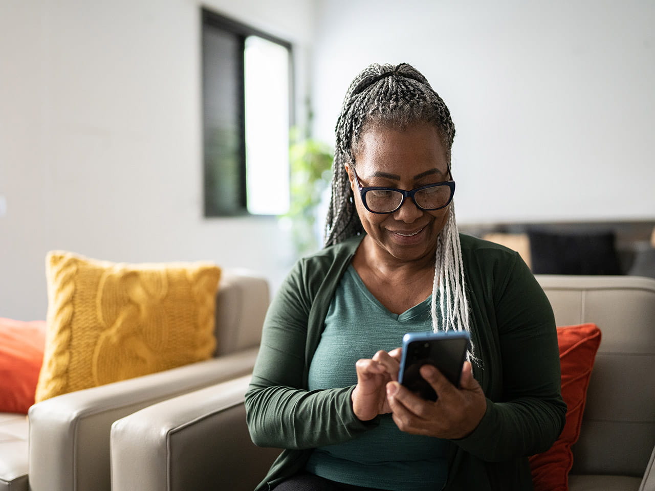 A woman sitting on a couch looking at her smartphone.
