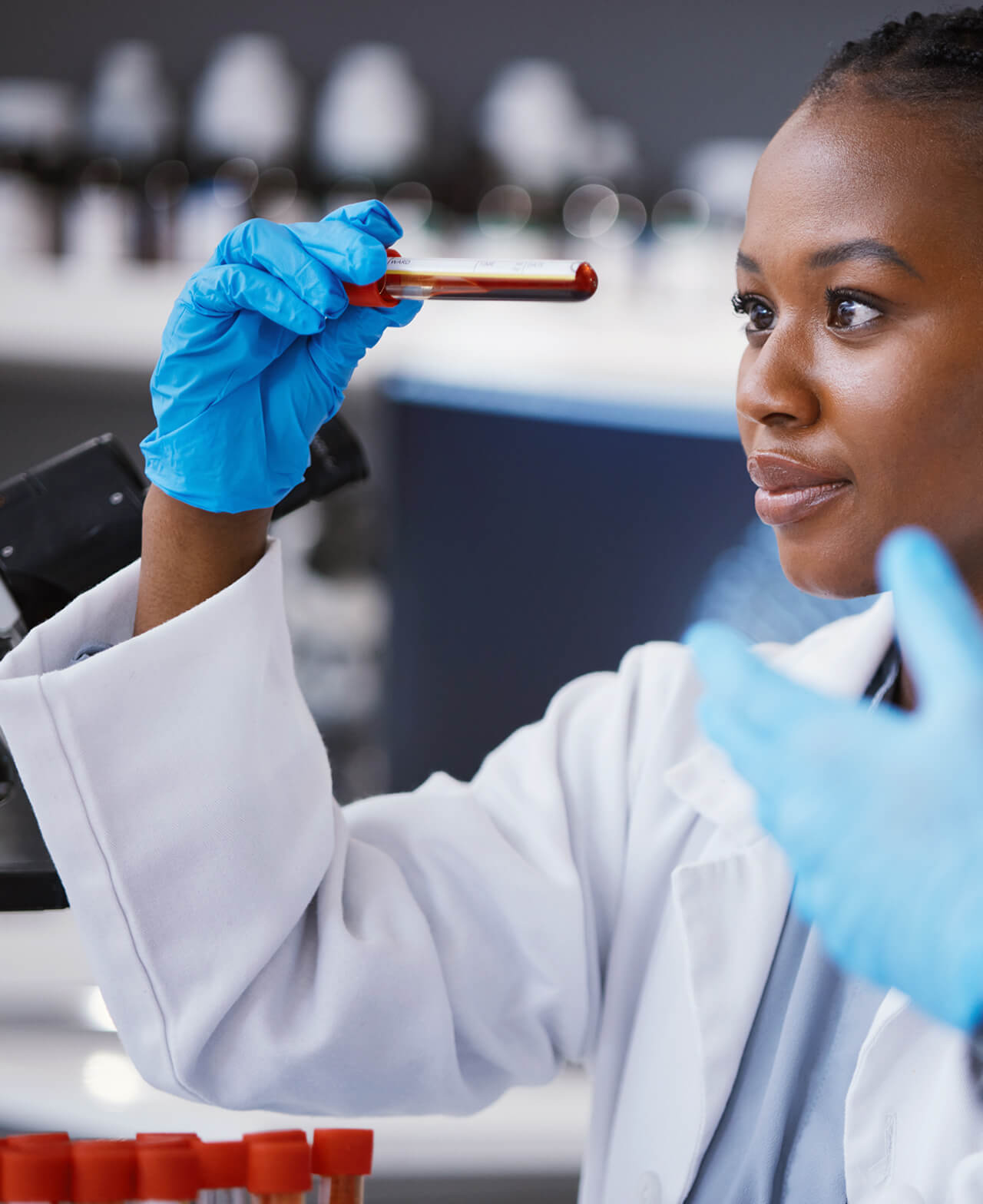 A lab technician examining a vial of blood.
