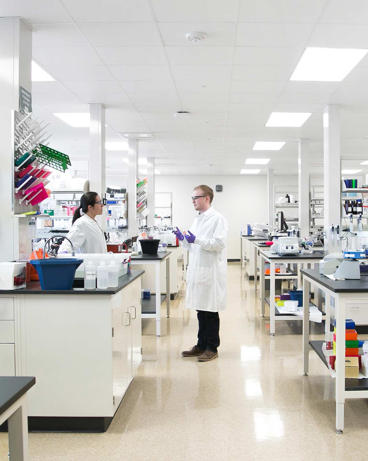 Two Exact Sciences technicians talking in a large lab.