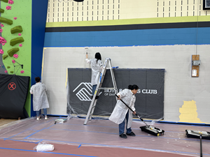 Three Exact Sciences team members and Athletes paint the walls of the Boys & Girls Club gym.