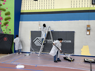 Three Exact Sciences team members and Athletes paint the walls of the Boys & Girls Club gym.