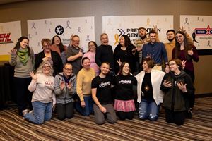 A group of event goers posing and laughing in front of a decorative wall