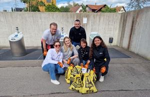 A group of volunteers smiling and proudly posing with filled trash bags.